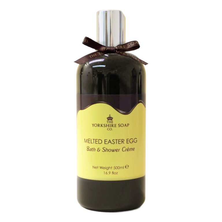 Walking Around Yorkshire With Chocolate All Around My Mouth | The Yorkshire Soap Company Easter 2024 Range A tall and wide cylindrical plastic bottle full of some dark brown liquid with a silver plastic lid, a dark brown bow tied around it, and a gradient dark brown and bright yellow label that has The Yorkshire Soap Company Melted Chocolate Easter Egg Bath & Shower Creme written in bold black writing and a picture of a black crown on it, on a white background.
