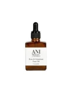 My Soft & Healthy Skin Will Be Back | Ani Skincare Rose And Geranium Face Oil A short square amber glass bottle full of some clear liquid with a black rubber pipette lid and a white label that has Ani Skincare Rose and Geranium Face Oil written in bold black writing on it, on a white background.