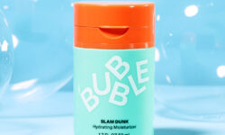 A short cylindrical mint green Plastic Bottle with a bright orange plastic lid that has Bubble Slam Dunk Hydrating Moisturiser written in bright white writing on it, on a white background.