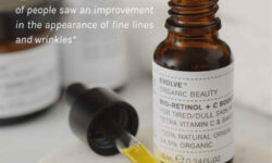 A short cylindrical amber Glass Bottle with a black Rubber Pipette Lid and a white label that has Evolve Organic Beauty Bio-Retinol + C Skin Booster written in bold black writing on it, on a white background.