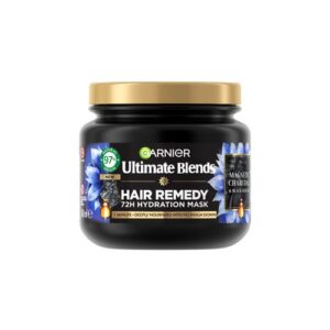 A short cylindrical black plastic Tub with a black plastic lid and a bright green label that has Garnier Ultimate Blends Balancing Hair Remedy Mask with Charcoal & Black Seed Oil written in bright white writing, a picture of a puddle of black charcoal, and a picture of some black seeds on it, on a white background.