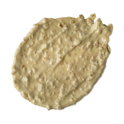 A medium circular puddle of some pale yellow face mask that has some pieces of Porridge running through it, on a white background.