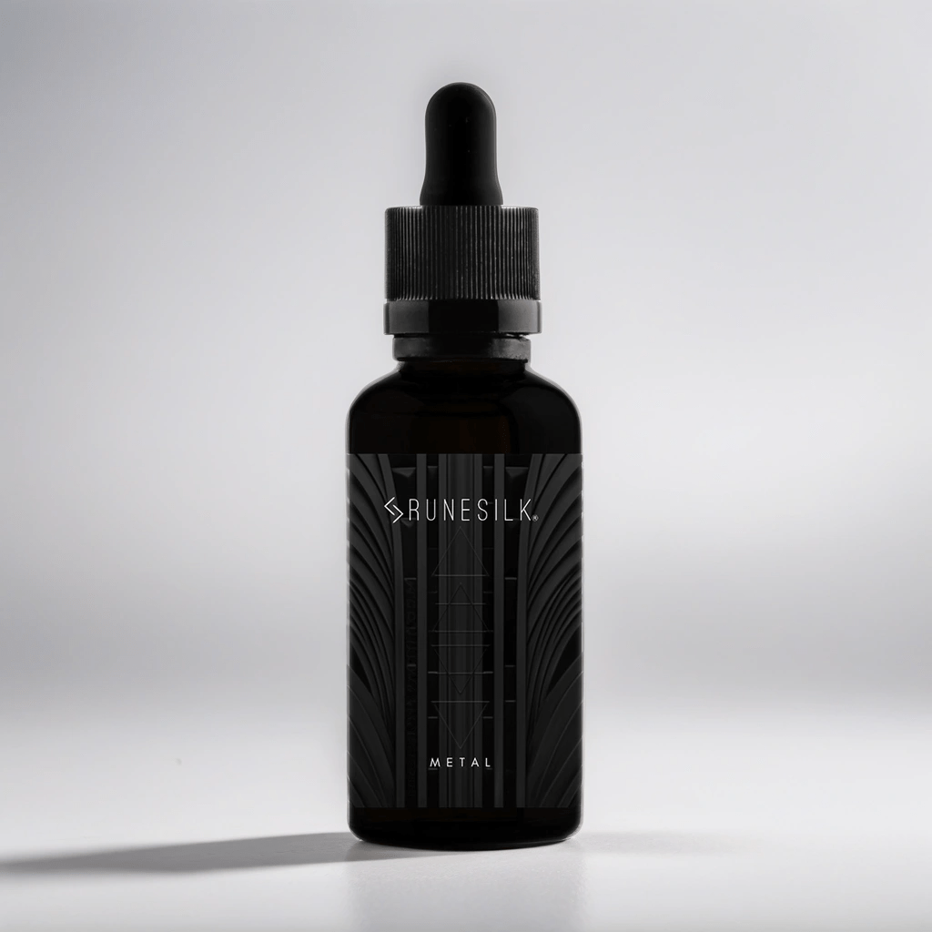 Blacksmiths Always Have Amazing Looking Beards | Runesilk Elements Metal Beard Oil A short cylindrical brown glass bottle with a black rubber pipette lid and a black label that has runesilk elements Metal beard oil written in bold black writing and a picture of a white geometric pattern on it, on a white background.