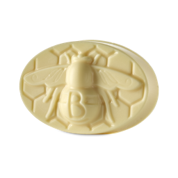 A medium golden yellow oval shaped block of solid massage Oil that has a bee engraved on it, on a white background.