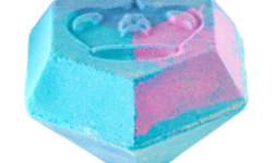A large gradient bright blue and pink diamond shaped bath bomb that has a crown engraved on the top of it and is covered in some silver lustre, on a white background.