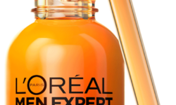 A short rounded cylindrical bright orange glass bottle with a black rubber pipette lid and a bright orange label that has L’Oreal Paris Men Expert Vitamin C Shot Serum written in bold black writing and Hydra Energetic written in bright white writing on it, on a white background.