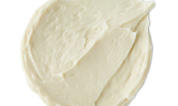 A medium circular puddle of some creamy ivory Facial sunscreen, on a white background.
