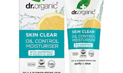 A short conical bright white plastic tube with a bright white plastic lid with a gradient bright teal and white label that has Dr. Organic written in bold black writing, Skin Clear written in bright white writing, Oil Control written in bright teal writing, and a picture of a dark green leaf, a bright yellow slice of Grapefruit and some droplets of water on it next to a tall rectangular gradient bright teal and white cardboard box that has Dr. Organic written in bold black writing, Skin Clear written in bright white writing, and oil control written in bright teal writing on it, on a white background.