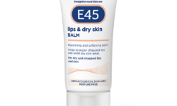 A short flat conical bright white plastic tube with a clear plastic lid that has E45 written in bright white writing, Lips & Dry Skin Balm written in dark blue writing, a picture of a dark blue oval, and a picture of a dark grey stripe on it, on a white background.