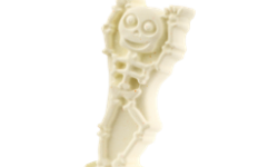 A tall bright white standing cartoon skeleton shaped bath bomb that has a smiling face engraved on it, on a white background.