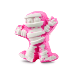A medium bright pink mummy shaped bath bomb that has some bright white bandages all over it and a surprised expression engraved on it, on a white background.