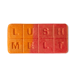 Marvellous Marzipan Magic | Lush Snowcake Soap and Snow Angel Bath Melt A tall rectangular gradient bright orange and red block of wax that has Lush engraved on it, on a white background.