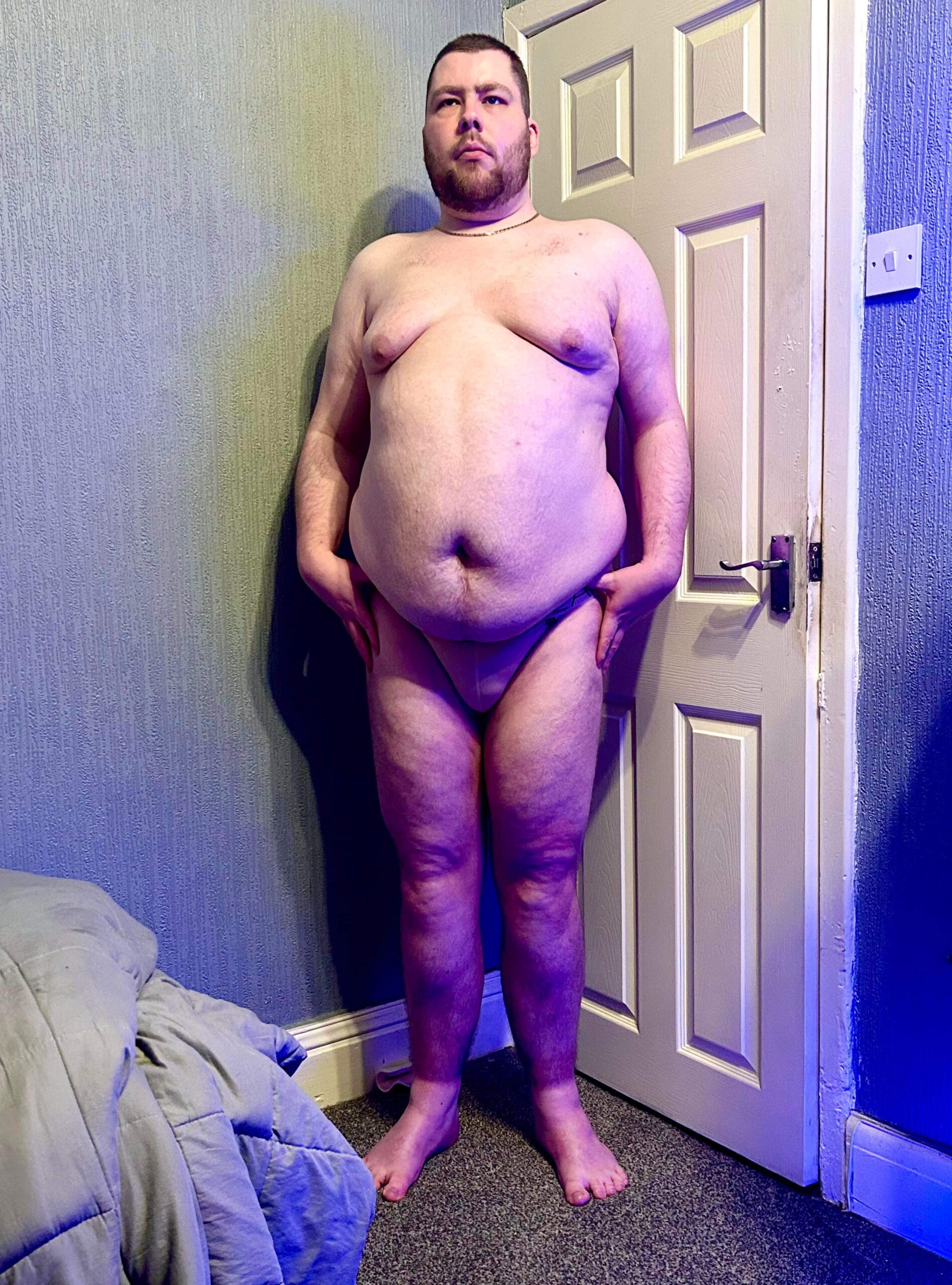 Don't Be Sad! It's Carnival! | Box Menswear Carnival 2.0 Tanga Briefs A tall bearded man with his hands on his hips wearing a pair of light beige tanga briefs with a black waistband that has Box Menswear written in bright white writing on it stood against a white wooden door.