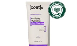 A tall flat conical bright white plastic tube with a dark purple plastic lid and a bright white label that has Coat’s Skin Purifying Hydrating written in bold black writing and Clay Cleanser written in dark purple writing on it, on a white background.