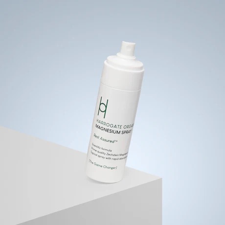 Walking Around Harrogate Is Actually Quite Relaxing | Harrogate Organics Magnesium Spray A tall cylindrical bright white plastic bottle with a bright white plastic lid and a bright white label that has Harrogate Organics Magnesium Spray written in bright green writing and a picture of two overlapping bright green letter h’s on it, on a white background.