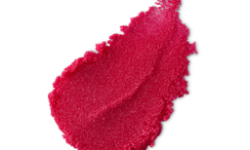 A medium circular puddle of some deep rosy pink lip scrub, on a white background.