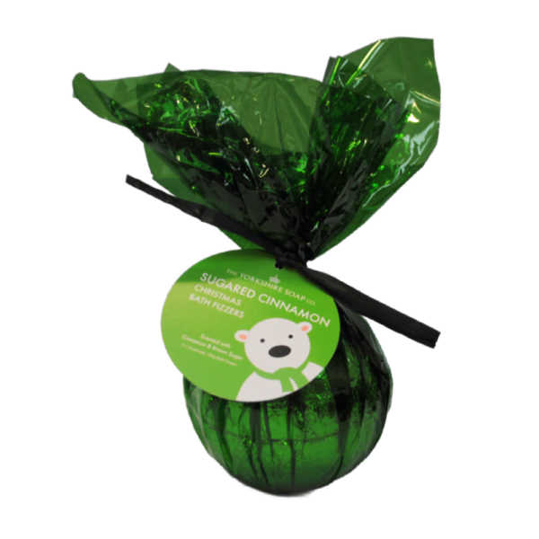 A Penguin Has Been Spotted Waddling Around Yorkshire This Christmas | The Yorkshire Soap Company Christmas 2024 Range A large spherical shaped bath bomb wrapped in some dark green cellophane and tied with a black ribbon with a dark green label that has The Yorkshire Soap Company Sugared Cinnamon Bath Bomb written in bright white writing and a picture of a White Bear wearing a dark green scarf on it , on a white background.
