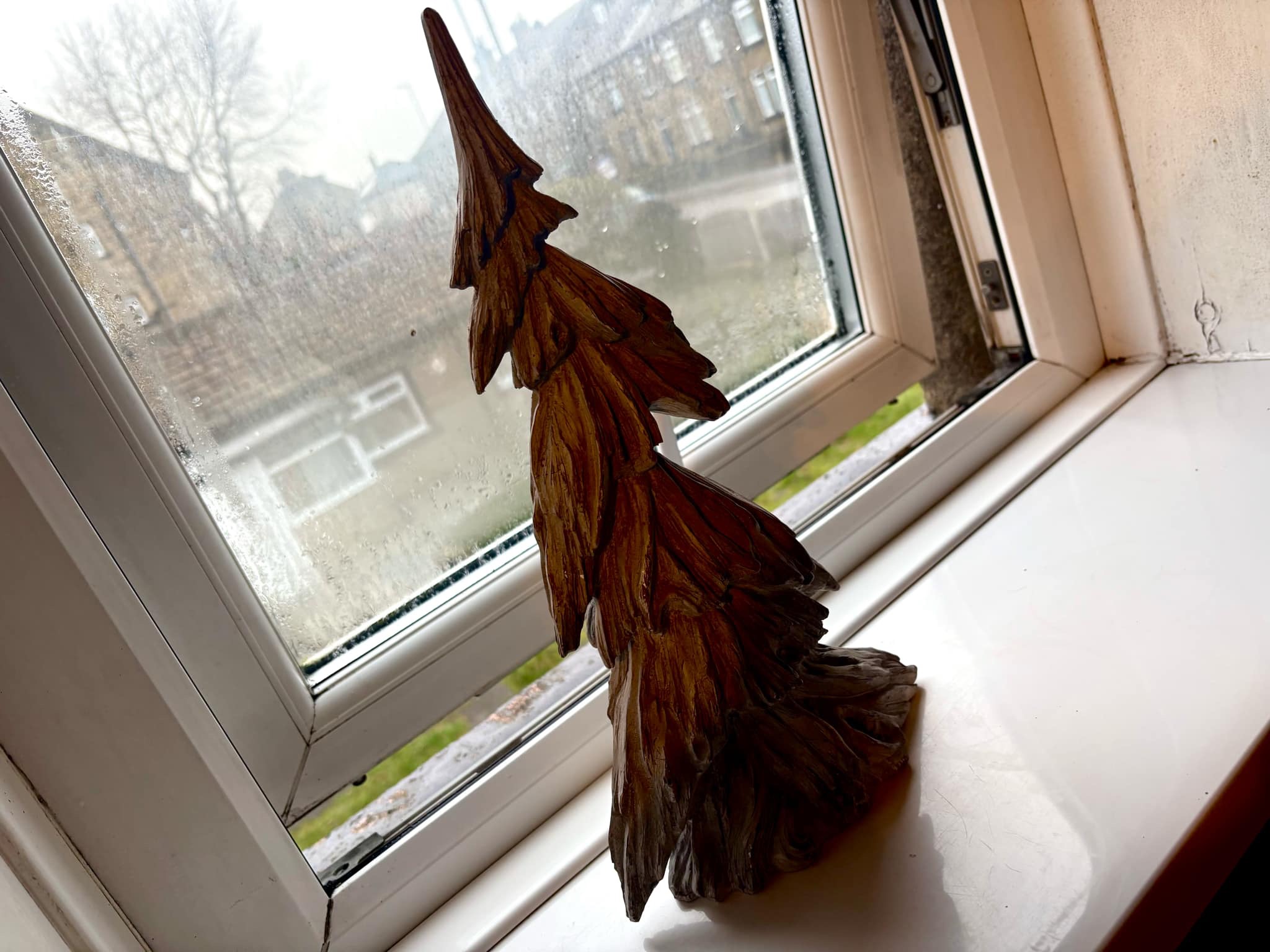 Luke Loves Christmas 2024 | How I've Decorated My Room This Year A large triangular bright white and grey resin Christmas Tree on a large rectangular glossy white windowsill infant of a large rectangular foggy glass window.