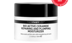 A short cylindrical bright white plastic tub with a black plastic lid and a bright white label that has The INKEY List Bio-Active Repairing & Plumping Ceramide Moisturiser written in bold black writing and a picture of a black stripe on it, on a white background.