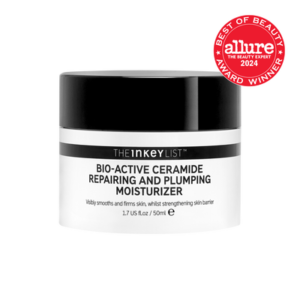 A short cylindrical bright white plastic tub with a black plastic lid and a bright white label that has The INKEY List Bio-Active Repairing & Plumping Ceramide Moisturiser written in bold black writing and a picture of a black stripe on it, on a white background.