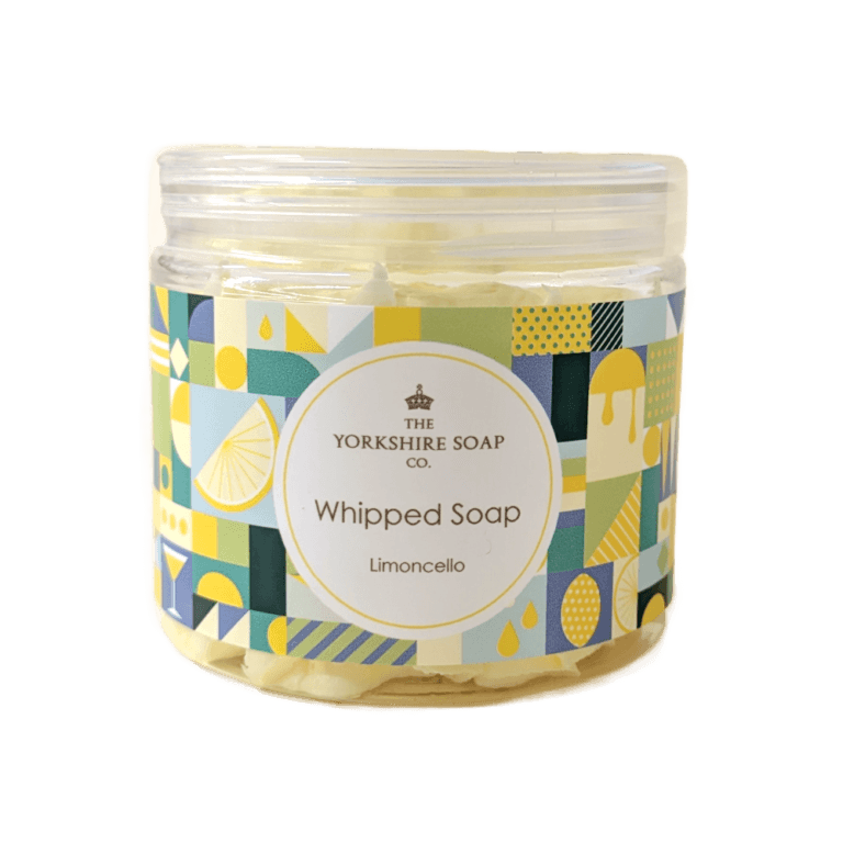 Bringing A Bit Of Italian Sunshine InTo My Yorkshire Bathroom | The Yorkshire Soap Company Whipped Soap Range A short cylindrical clear Plastic Tub full of some golden yellow whipped soap with a clear Plastic Lid and a bright blue, green, white and yellow multicoloured label that has The Yorkshire Soap Limoncello Whipped Soap written in black writing inside a white circle and some pictures of some bright yellow lemons on it, on a white background.