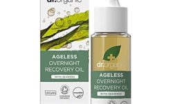 A short cylindrical glass bottle full of some translucent golden yellow liquid with a white rubber pipette lid and a light green label that has Dr. Organic Seaweed Ageless Overnight Recovery Oil written in bright white writing and a picture of a dark green leaf with a white cross over it on it next to a short rectangular light green cardboard box that has Dr. Organic Seaweed Ageless Overnight Recovery Oil written in bright white writing on it, on a white background.