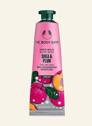 Purple Rain, Purple Rain | Lush Plum Rain Shower Gel & Plum Rain Body Spray A long and thin conical metallic bright pink tube with a metallic dark green lid and a bright pink label that has The Body Shop Shea & Plum Hand Balm written in dark green writing and some pictures of some bright purple plums on it, on a white background.
