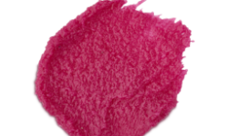 A medium circular puddle of some bright Bubblegum Pink body scrub that has some pieces of Fine Sea Salt running through it, on a white background.