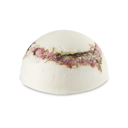 As I See The Pretty Flowers That Are Falling One By One | Lush White Day 2025 Range | Ad A medium half sphere shaped block of creamy white solid body scrub that has some pieces of granulated sugar running through it and some bright pink petals in the centre of it, on a white background.
