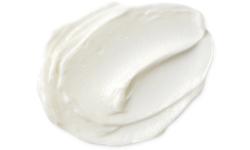 A medium circular puddle of some creamy white scalp treatment, on a white background.
