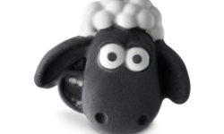 A medium creamy white sheep’s head shaped Bath Bomb that has a black face with some big eyes, a wide smile, and some floppy ears engraved on it and a bundle of creamy white wool on top of it’s head, on a white background.