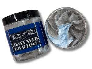 A tall cylindrical clear plastic tub full of some gradient bright grey and light blue whipped soap with a black plastic lid and a light blue label that has Tales of Toria I Don’t Need Your Love Whipped Soap written in bright white writing and some pictures of some light blue diamonds on it, on a white background.