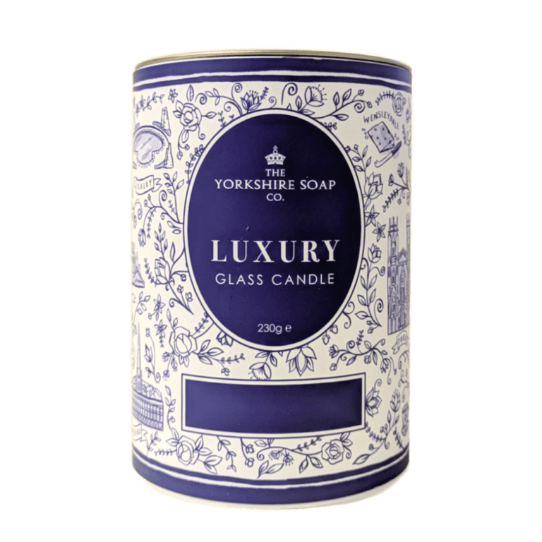 The Best Smelling Afternoon Tea In Yorkshire | The Yorkshire Soap Company Afternoon Tea Glass Candle A tall bright white cardboard tube that has The Yorkshire Soap Company Afternoon Tea Glass Candle written in bright white writing inside a dark blue oval, a picture of a black crown, and some pictures of some bright white leaves on it, on a white background.
