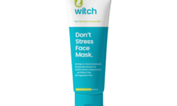 A tall conical turquoise plastic tube with a bright white plastic lid that has Witch Don’t Stress Face Mask written in dark blue writing and a picture of a dark green leaf on it, on a white background.