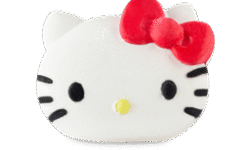 A medium bright white cat’s head shaped bath bomb that has some small black eyes, some black whiskers, a small bright yellow nose, and a large bright red Bow engraved on it, on a white background.