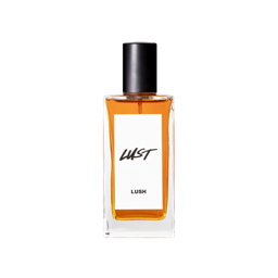 A short rectangular glass perfume bottle full of some translucent red amber liquid with a metallic black lid and a white label that has Lush Lust perfume written in bold black writing on it, on a white background.