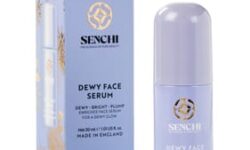 A tall cylindrical light purple glass bottle with a light purple plastic lid that has Senchi Dewy Face Serum written in bright white writing on it next to a tall rectangular light purple cardboard box that has Senchi Dewy Face Serum written in bright white writing on it, on a white background.