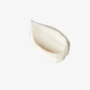 A medium circular puddle of some glossy creamy white moisturiser, on a white background.