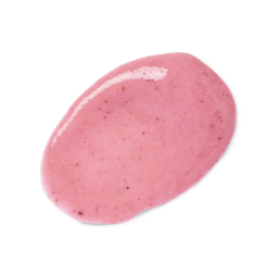 A medium circular puddle of some creamy pastel pink body scrub that has some pieces of Tagua Nut Powder, Ground White Rice, and Pomegranate Seed Powder running through it, on a white background.,