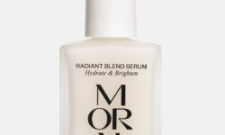 A short square bright white glass bottle with a bright white rubber pipette lid and a bright white label that has Moral Radiant Blend Serum written in bold black writing on it, on a white background.