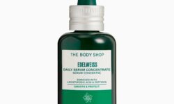 A short cylindrical bright green glass bottle with a dark green Rubber Pipette Lid that has The Body Shop Edelweiss Daily Serum Concentrate written in dark green writing on it, on a white background.