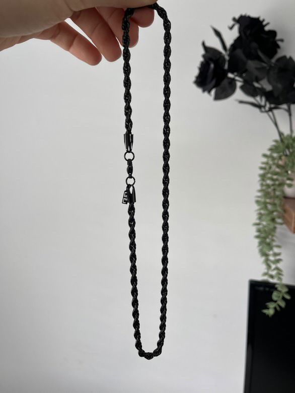 His Special Day | Father's Day 2025 Gift Guide | Gifted A hand holding a metallic black rope with a metallic silver clasp and a small metal charm that has a Letter E engraved on it, on a white background.