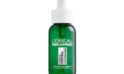 A short cylindrical dark green glass bottle with a bright white rubber pipette lid and a dark green label that has L’Oreal Paris Men Expert Derma Control Anti-Blemish Serum written in bright white writing on it, on a white background.