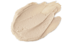 A medium circular puddle of some thick creamy ivory white face mask, on a white background.