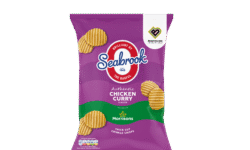 A tall rectangular bright purple plastic bag that has Seabrook written in gradient bright blue and red writing, Chicken Curry written in bright white writing, and some pictures of some golden brown crinkle cut crisps on it, on a white background.