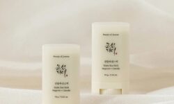A short rounded rectangular creamy white plastic tube with a circular twist up mechanism at the bottom of it that has Beauty of Joseon Mugwort + Camilia Matte Sun Stick SPF50+ PA++++ written in bold black writing on it next to a short rounded rectangular creamy white plastic tube with a circular twist up mechanism at the bottom of it that has Beauty of Joseon Mugwort + Camilia Matte Sun Stick SPF50+ PA++++ written in bold black writing on it, on a creamy white background.