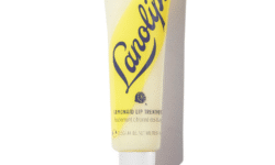 A short and thin conical bright white plastic Tube with a bright white Plastic Lid that has Lanolips written in dark blue writing, Lemonade Lip Treatment written in bold black writing, a picture of a bright yellow slice of Lemon, and a picture of a bright yellow stripe on it, on a white background.