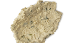A medium circular puddle of some creamy white face mask that has some pieces of Brown Rice Amazake running through it, on a white background.