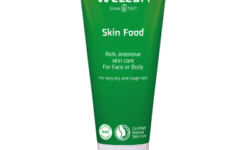 A tall conical metallic green tube with a bright white plastic lid that has Weleda Skin Food written in bright white writing on it, on a white background.