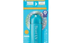 A short cylindrical bright turquoise plastic bottle with a bright turquoise plastic lid that has Bioré UV Aqua Rich Aqua Protect Lotion SPF50+ PA++++ written in bright white writing on it attached to a large rectangular piece of bright blue cardboard that has a picture of a bright orange and white stripe on it, on a white background.